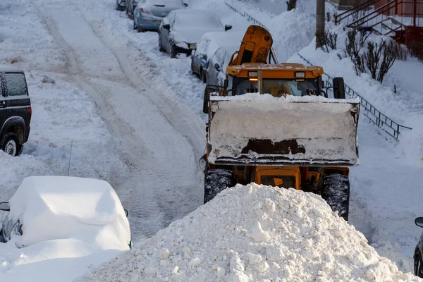 冬の日に住宅近くの駐車場から雪を取り除くトラクター — ストック写真