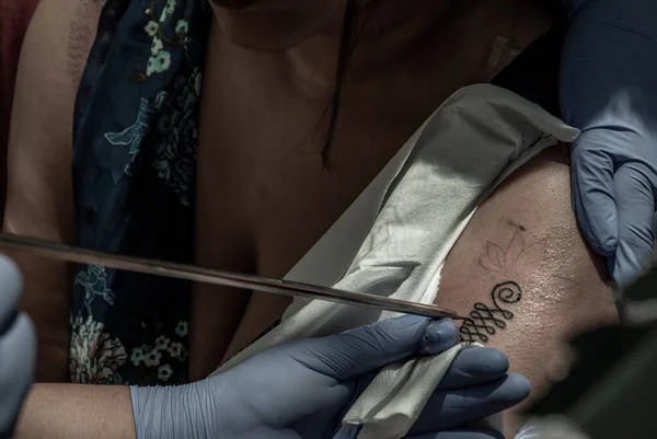 纹身泰国风格的概念 纹身艺术家用尖尖的金属在女孩的手臂上纹身 — 图库照片