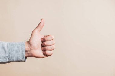 Male hand showing thumb up on beige background