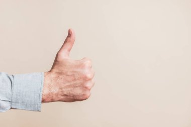 Male hand showing thumb up on beige background