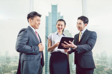 Gülümseyen iş adamları dijital tablete bakıyor