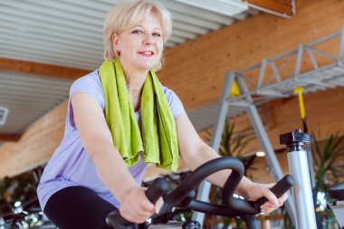 Spor salonunda bisiklete binen son sınıf öğrencisi.