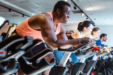 Spor salonunda spor bisikletli Afrikalı adam ve arkadaşları