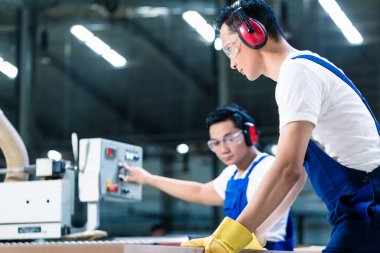 Marangozlukta iki ahşap işçisi tahta kesiyor