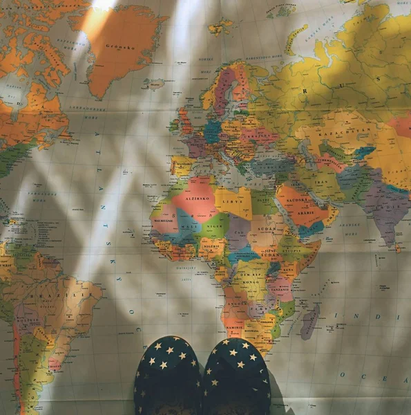 夏の旅行のための美しいコンセプト 世界地図で子供用の小さな靴 夏の休暇や休日を計画 — ストック写真