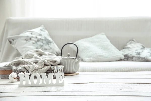 A teapot with hygge decor details and a decorative word home on the table in the living room