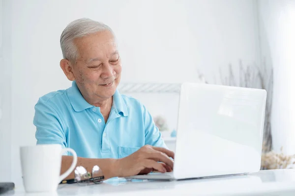 快乐的老年人在笔记本电脑上工作 拿着咖啡杯 — 图库照片
