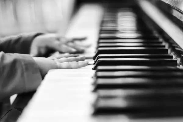 Child playing piano on background, close up