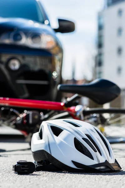 自動車事故後のアスファルト上の自転車用ヘルメットのクローズアップ — ストック写真