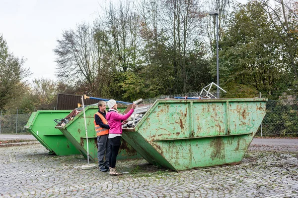 リサイクルする容器にスクラップ金属を入れる女性 — ストック写真