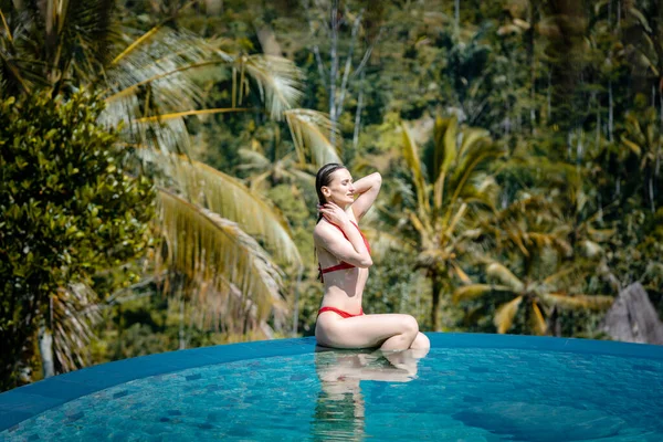 プールの水の中に座っている熱帯休暇中の女性 — ストック写真