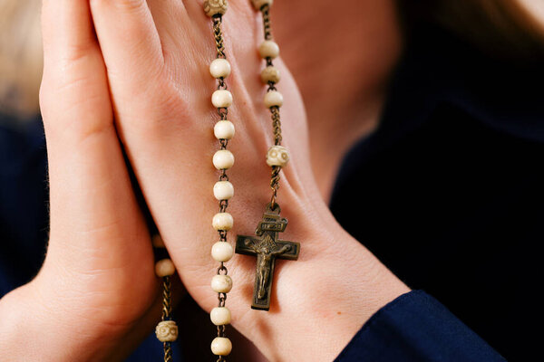young woman praying with rosary to God