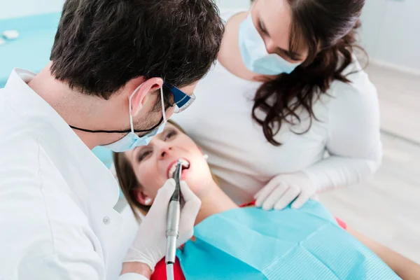 クリニックで女性を治療する歯科医とアシスタント — ストック写真