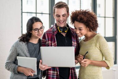 Genç ekip iş sunumunu ofisteki laptopta inceliyor.