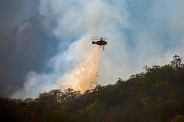Helikopter orman yangınına su döküyor.