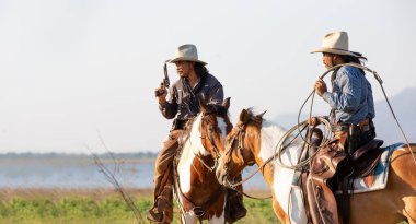 cowboy riding horse against sunset