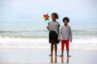 Çocuklar deniz kıyısındaki kumsalda oynayıp eğleniyorlar.