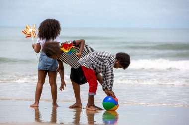 Çocuklar deniz kıyısındaki kumsalda oynayıp eğleniyorlar.