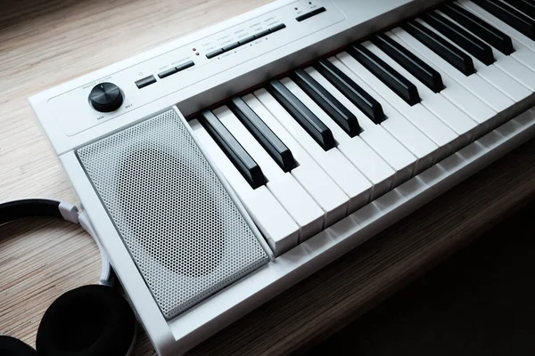木製のテーブルにヘッドフォン付きの白い音楽キーボード — ストック写真