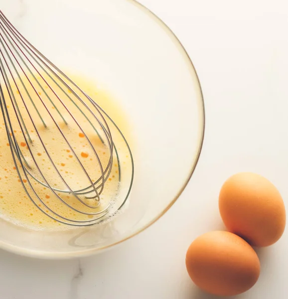 自家製食品フラットレイとして大理石のテーブルの上にボウルに卵を混合すること トップビュー食品ブランド写真フラットレイと料理ブログ メニューや料理本のデザインのためのレシピ — ストック写真