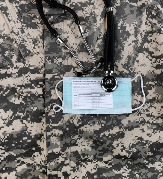 Covid 19予防接種記録カード 軍事制服のパーソナルフェイスマスクと聴診器 — ストック写真