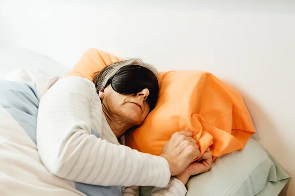 An old lady sleeping using a face mask in a modern bedroom with copy space