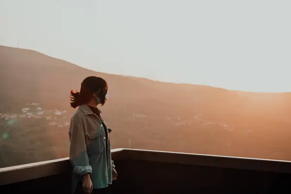 Молодая Женщина Маске Смотрящая Горы Балкона Время Супер Красочного Заката — стоковое фото