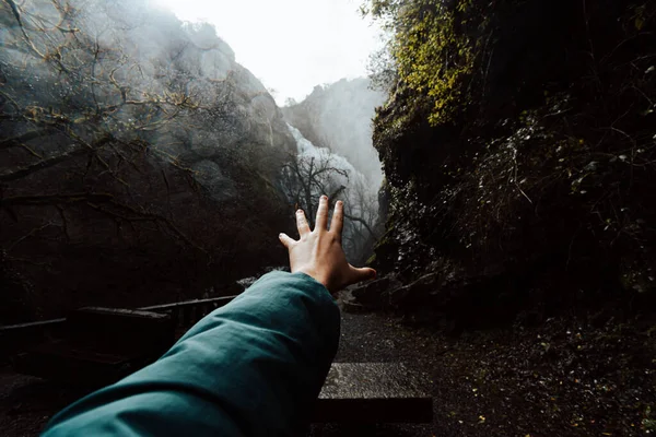 Inspirational shot of a hand in front of a waterfall on moody tones with copy space