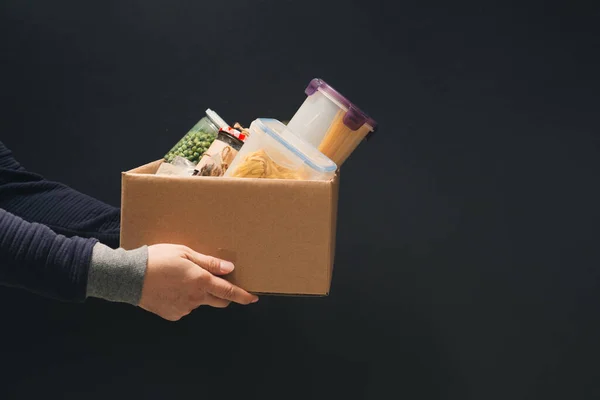 Ein Mann Mit Einer Spendenbox Mit Verschiedenen Produkten Auf Dunklem — Stockfoto