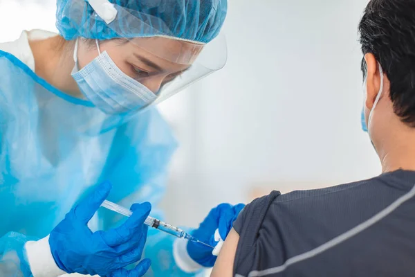 医生或护士戴着长袍 面具和眼罩来帮助注射病人 — 图库照片