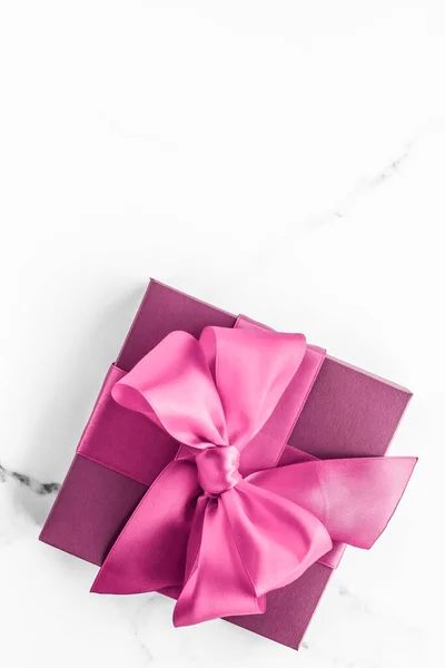 Pink gift box with silk bow on marble background, girl baby shower present and glamour fashion gift for luxury beauty brand, holiday flatlay art design