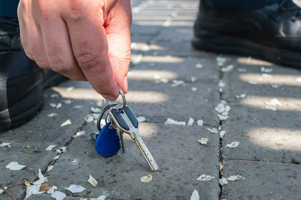 男は道路に横たわるキーの束を拾う — ストック写真