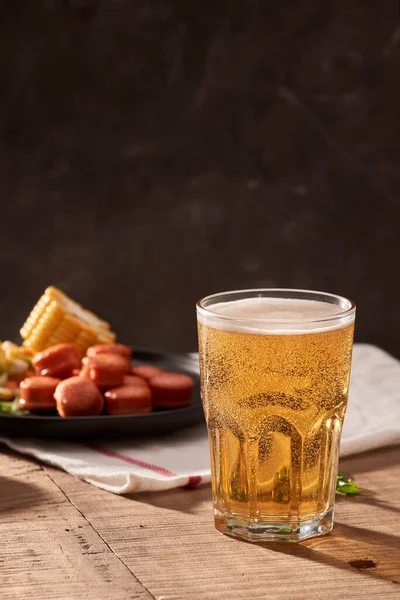 ビールと食欲をそそるビールのおつまみセット テーブルにマグカップビール焼きソーセージソース添え — ストック写真