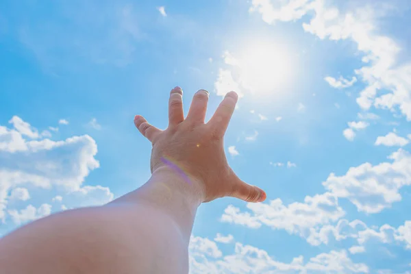 hand of a man trying to reach the sun and heaven