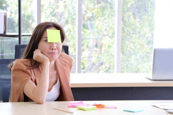 Asian businesswomen look and write a post-it note on face to relax and smile from work