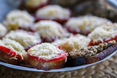 Tabakta rendelenmiş peynir ve domatesli taze bir sandviç.