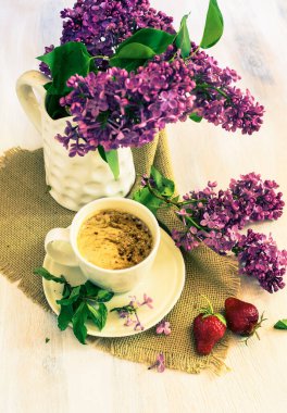 Bahar leylağı çiçekleri ve bir fincan kahve. 