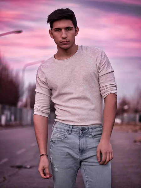 一个穿着白色毛衣的英俊年轻人站在街上 — 图库照片