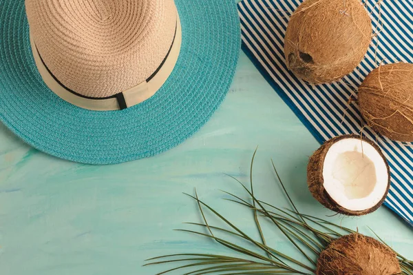Summer composition or layout. Tropical palm leaves, hat, glasses, beach towel, coconut on a background of sea greens. The concept of the summer season and heat. Flat lay, top view, copy space