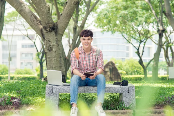 Jeune Homme Assis Sur Banc Dans Parc Lisant Livre Souriant — Photo