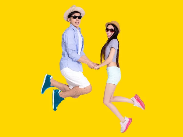 サングラスの若いカップルと一緒にジャンプ 黄色の背景に孤立 — ストック写真