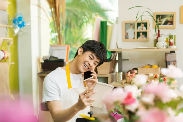 Smiling Asian Male Florist Calling Smartphone Making Notes Flower Shop — 图库照片