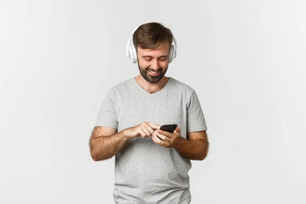 Retrato Del Atractivo Hombre Moderno Sonriendo Mirando Teléfono Móvil Escuchando — Foto de Stock