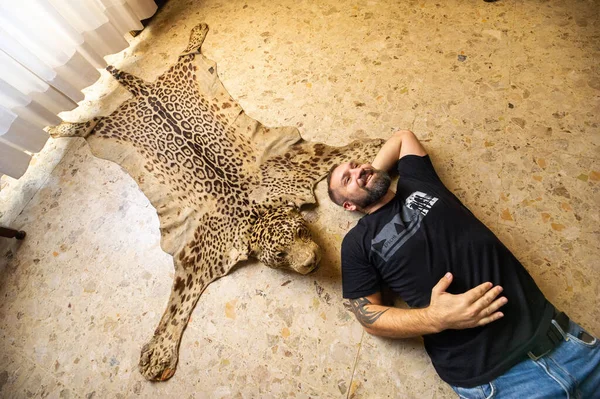 Мужчина Лежит Полу Рядом Кожей Мертвого Леопарда — стоковое фото