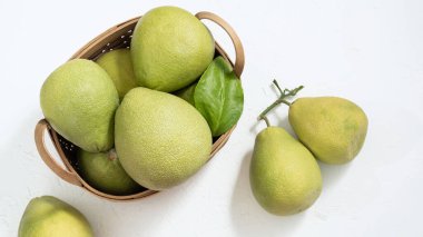 Taze pomelo, pumelo, greyfurt, bambu sepetinde beyaz çimento arka planında Shaddock. Sonbahar mevsimlik meyveler, üst manzara, düz yatış, masa üstü çekimi.