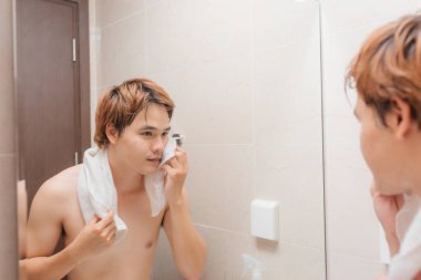 çekici bir adam aynada yüzünü kurutma