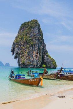 MAYA BAY, THAILAND - 14 Nisan 2014: Popüler Maya Körfezi 'ne yanaşan geleneksel Tayland uzun kuyruklu teknelerinin üzerinde dramatik karst coğrafyası duruyor.