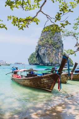 MAYA BAY, THAILAND - 14 Nisan 2014: Popüler Maya Körfezi 'ne yanaşan geleneksel Tayland uzun kuyruklu teknelerinin üzerinde dramatik karst coğrafyası duruyor.