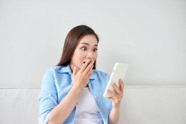 Heyecanlı kadın evde oturma odasında kanepede yatan bir cep telefonu üzerinde metin okuma