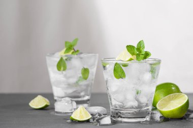 Limonlu mojito kokteylleri ve gri bir arkaplanda nane şekeri.